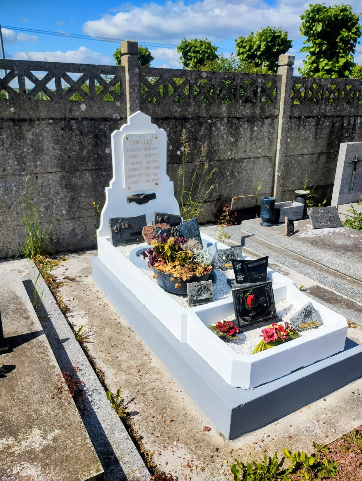 Un monument clair avec plaques et fleurs